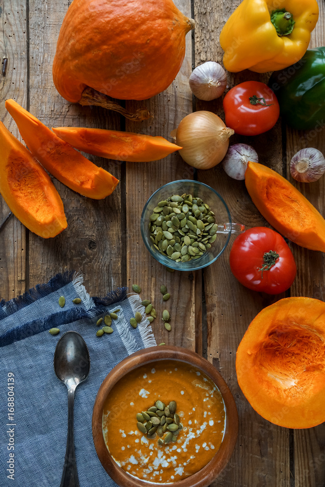 Traditional homemade pumpkin soup with seads, cream and vegetables on rustic wooden table Traditional homemade pumpkin soup with seads, cream and vegetables on rustic wooden table