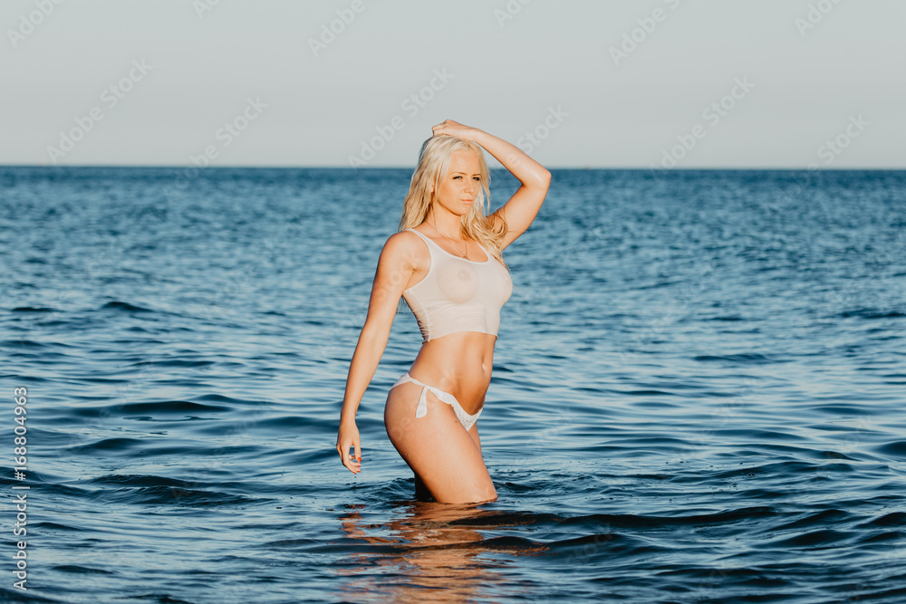 Sexy woman in wet t-shirt playing on water at beach over sea. Summer time  Stock Photo | Adobe Stock