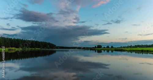Time lapse clip of evening fluffy curly rolling clouds mirror in lake