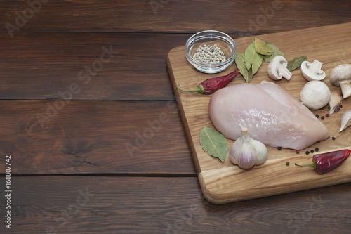 Fresh meat. Chicken fillet with chili, spices and rosemary on a cutting board. photo