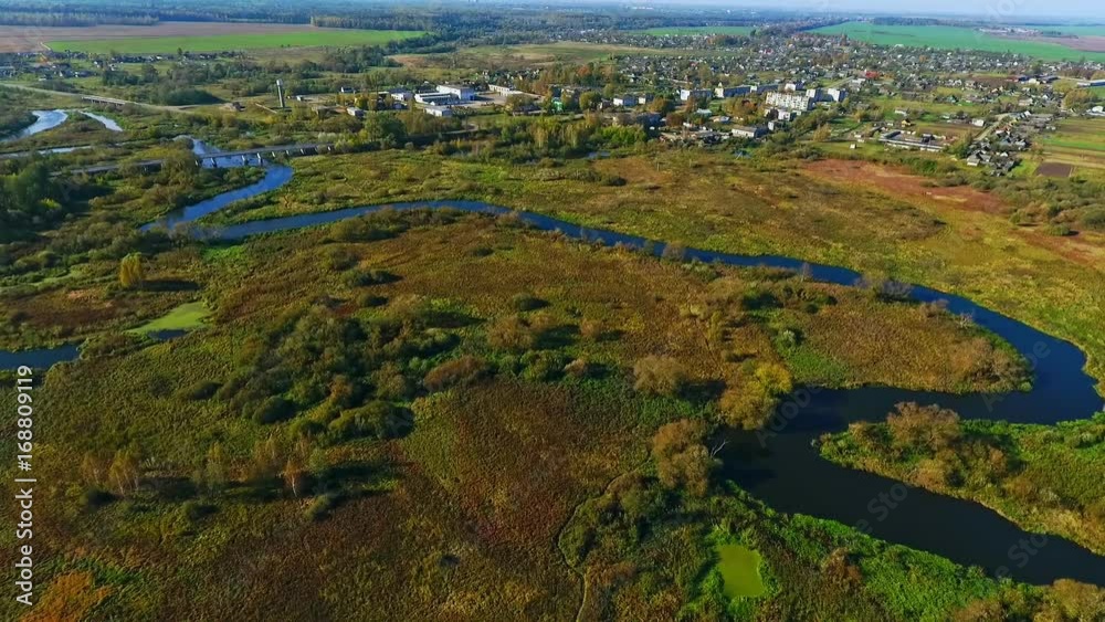 Aerial river landscape. River in forest. View from above. Sky view of meandering river in forest near city. Aerial landscape river forest. Drone view of city near autumn forest