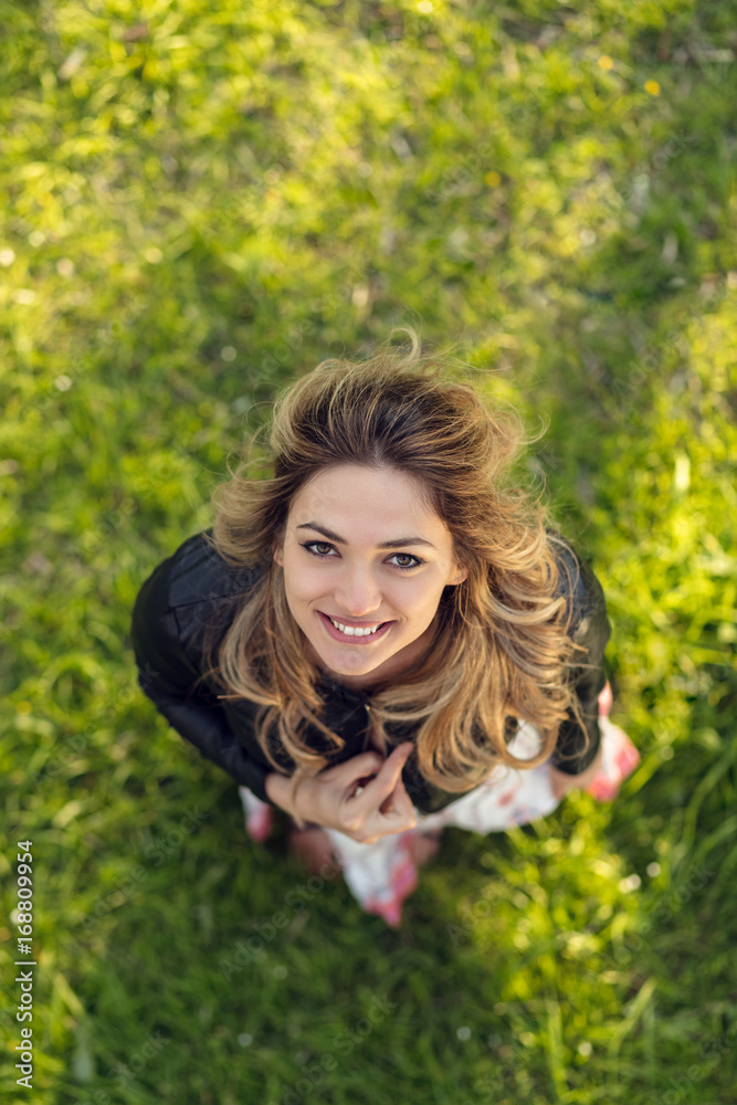 high angle view of beautiful happy girl smiling at camera while standing on green grass high angle view of beautiful happy girl smiling at camera while standing on green grass