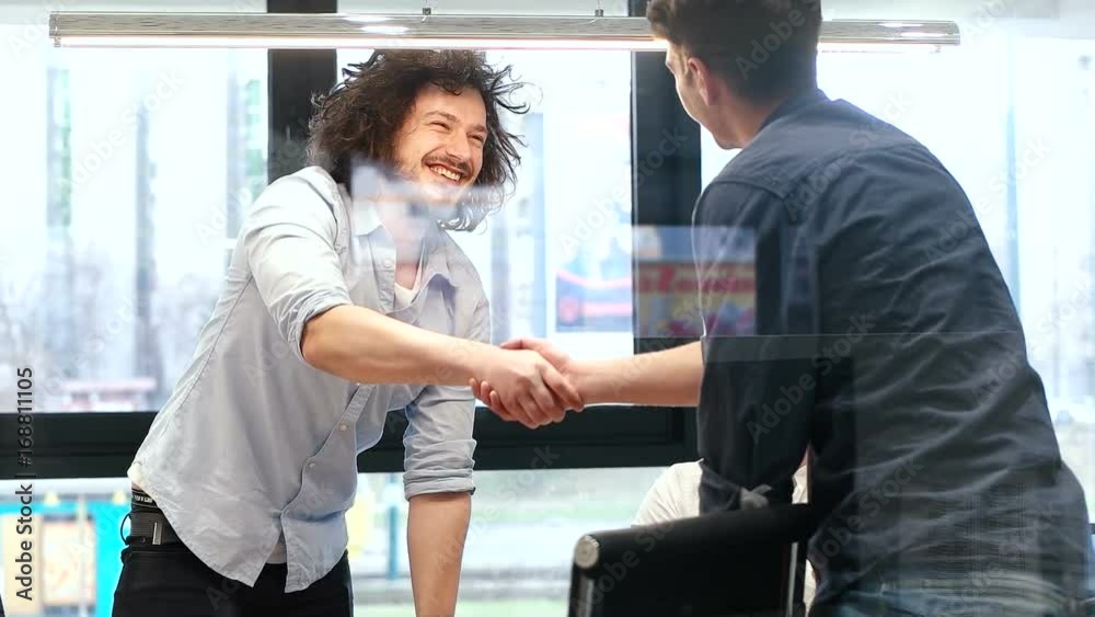 Coworkers sitting at business meeting in office. Men shaking hands while discussing partners agreement Coworkers sitting at business meeting in office. Men shaking hands while discussing partners agreement