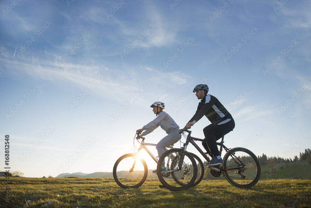 Happy mountainbike couple outdoors have fun together on a summer afternoon