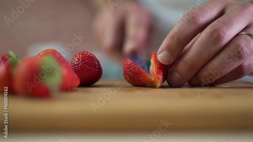 Man cuts strawberries clsoe up. photo