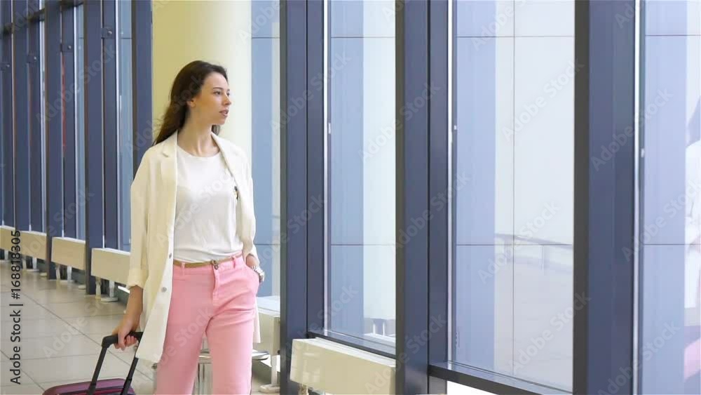 Young woman with baggage in international airport walking with her luggage. Airline passenger in an airport lounge waiting for flight aircraft Young woman with baggage in international airport walking with her luggage. Airline passenger in an airport lounge waiting for flight aircraft