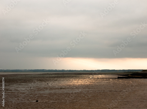 sunsetting in the distance stunning light over mudflats casting glow pretty beach