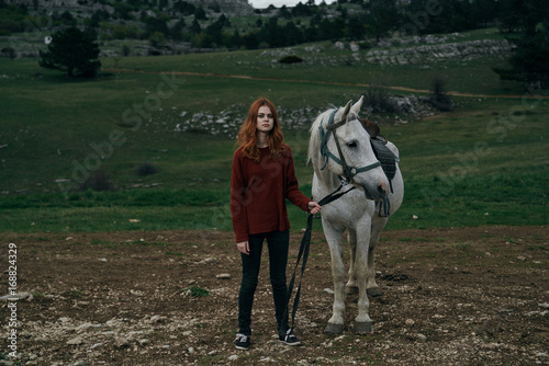 Young beautiful woman holds a horse, nature, mountains, hills