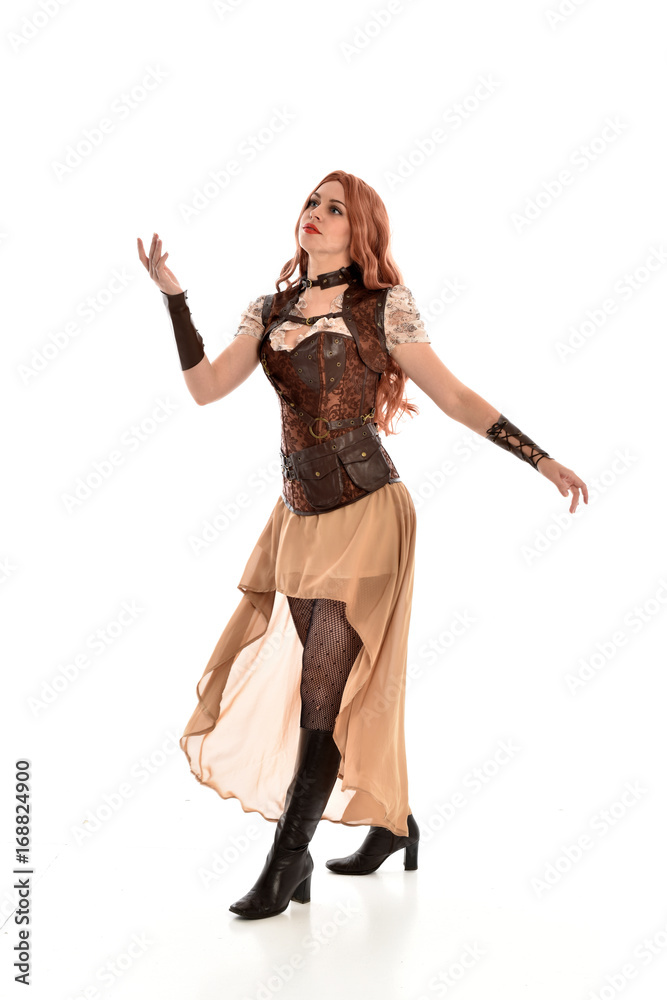 full length portrait of red haired lady wearing steampunk inspired outfit, standing pose against a white background.