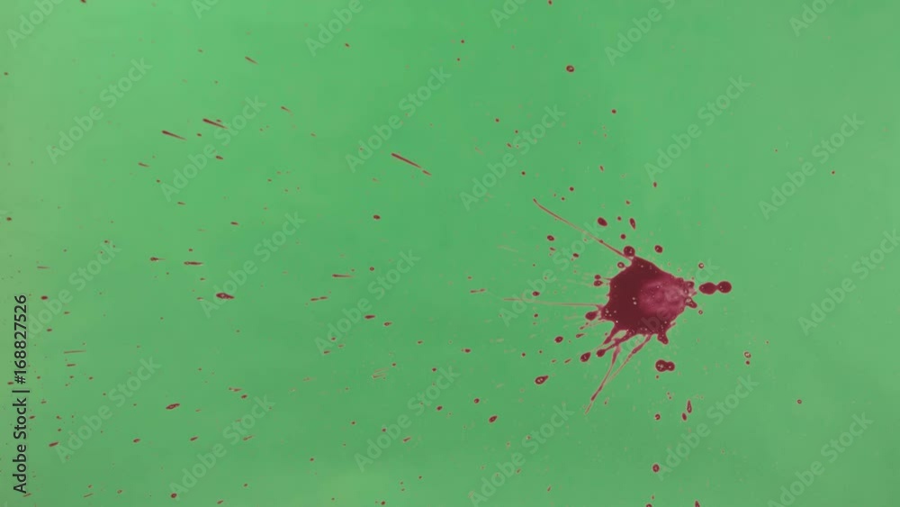 Red ink splatter over green screen background. Close-up shot