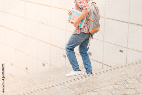 Cropped image of male student running with book in hands