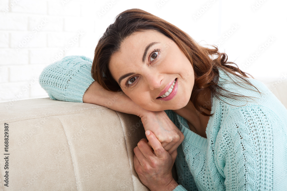 Attractive middle aged woman looking in camera relaxing at home. The beautiful face close up. Attractive middle aged woman looking in camera relaxing at home. The beautiful face close up.
