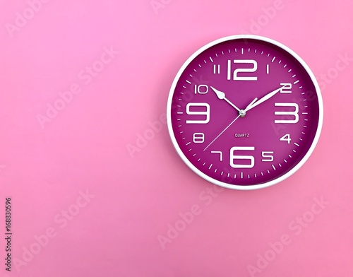 Closeup A deep pink wall clock set on pink background.The concept of" The time is going on."Top view with Copy Space. Selective focus.
