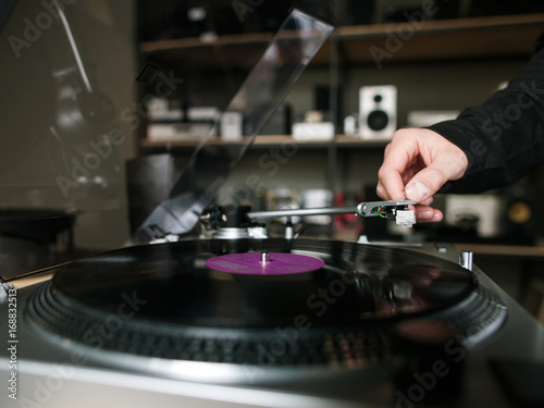 Vinyl record closeup. Retro musical shop. Unrecognizable male listening to music, modern turntable