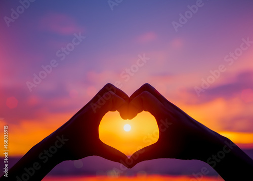 Silhouette the woman hands to be heart shape on sunset background. Happy, Love, Valentine's day idea, sign, symbol, concept.