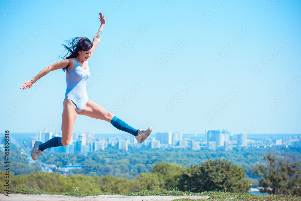 Exercises at city park. Lady exercising outdoors. Concept of healthy lifestyle. Portrait of athletic young woman resting on a nature. Beautiful woman at the park on a sunny day, city background Exercises at city park. Lady exercising outdoors. Concept of healthy lifestyle. Portrait of athletic young woman resting on a nature. Beautiful woman at the park on a sunny day, city background