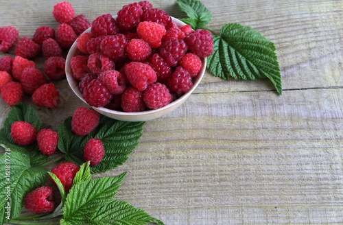 Fresh berries from the garden in a Cup on a wooden table. Raspberry With green leaves