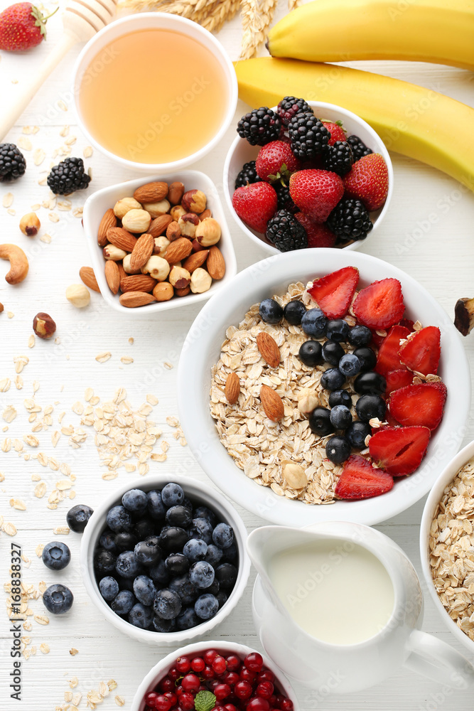 Oat flakes with berries, honey and nuts on wooden table Oat flakes with berries, honey and nuts on wooden table