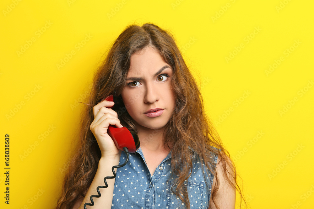 Portrait of young woman with red phone on yellow background Portrait of young woman with red phone on yellow background