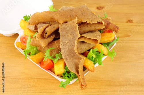 Take away kebab meat and chips with salad in an open fast food box
