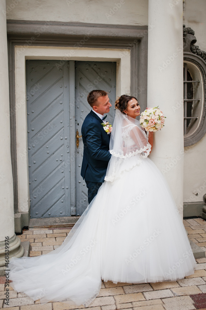 Amazing wedding couple enjoying each other's company by standing next to the columns of a church. Amazing wedding couple enjoying each other's company by standing next to the columns of a church.