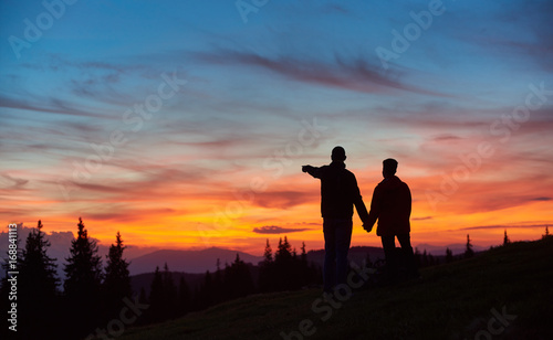Loving couple enjoying sunset while hiking in the mountains together. Man pointing to the sky copyspace love people affection romance nature landscape travelling