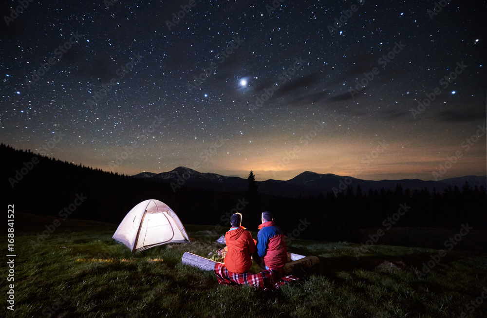 Night Camping In The Mountains Rear View Of Romantic Couple Tourists Have A Rest At A Campfire Near Illuminated Tent Under Night Starry Sky Low Light Stock Photo Adobe Stock