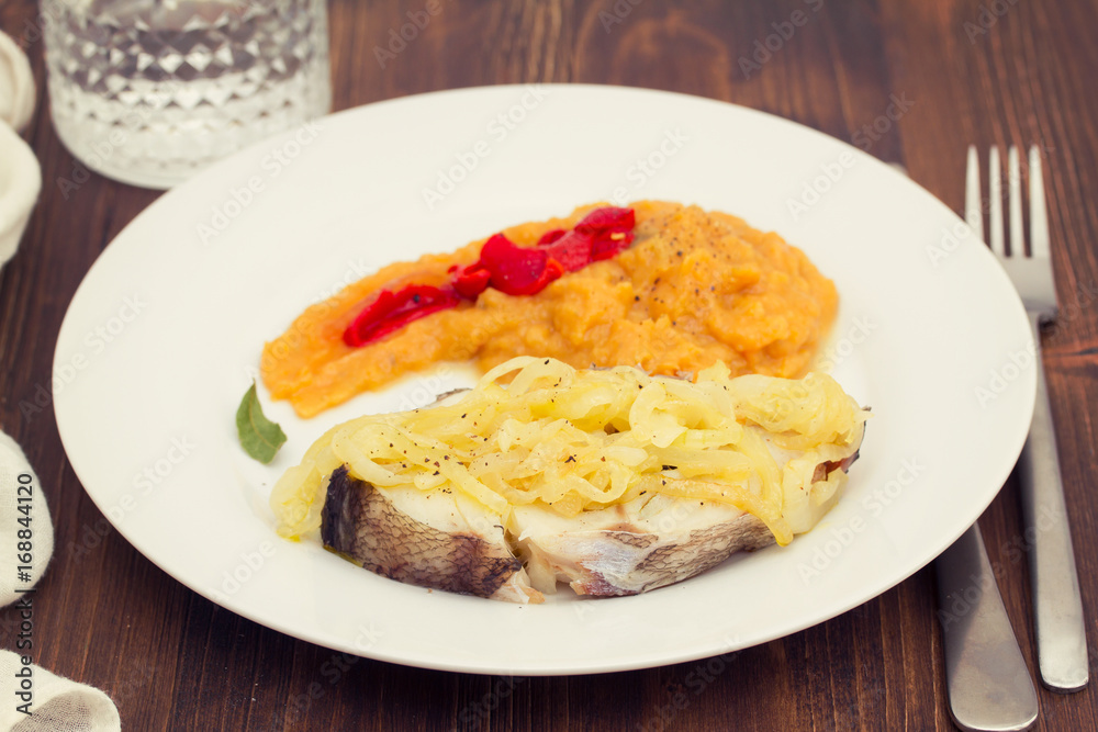 boiled fish with onion and pumpkin puree on white plate