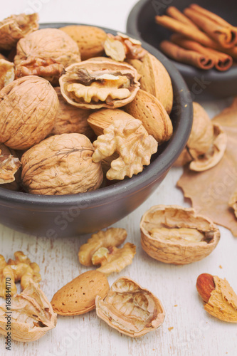 walnuts and almond on black bowl on wooden background