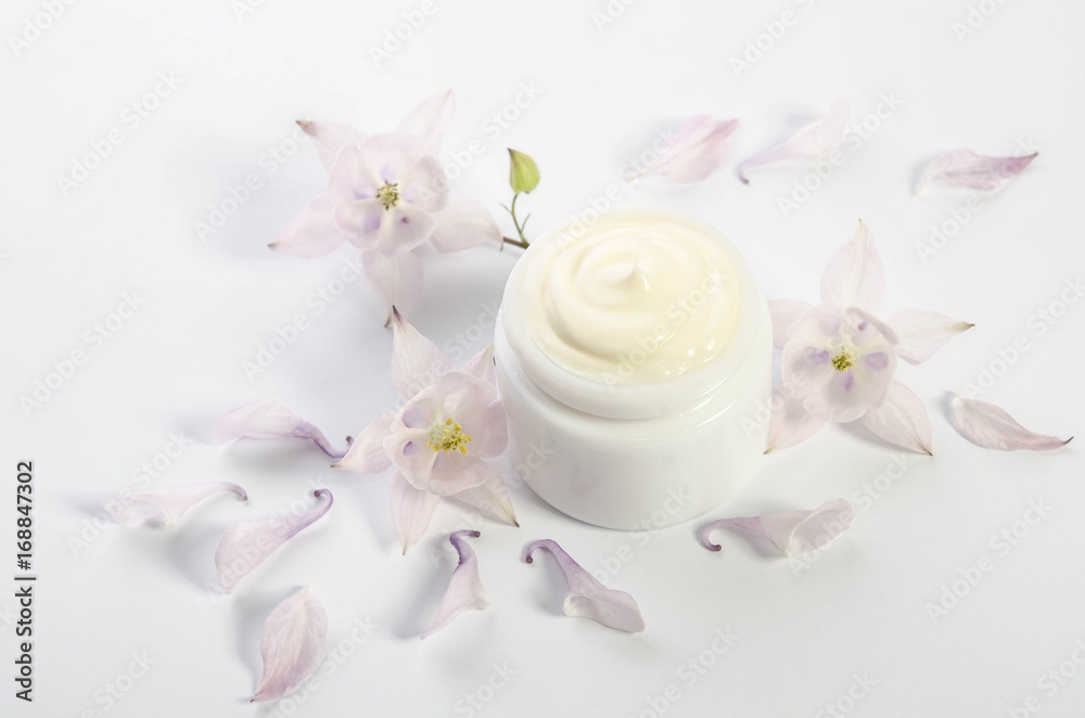 Cute flowers and petals and a jar of natural body cream isolated on white background Cute flowers and petals and a jar of natural body cream isolated on white background