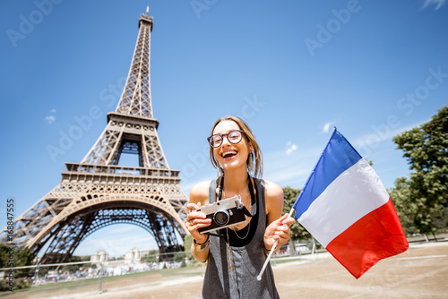 Young and happy woman tourist with french flag and photo camera in front of the Eiffel tower in Paris © rh2010