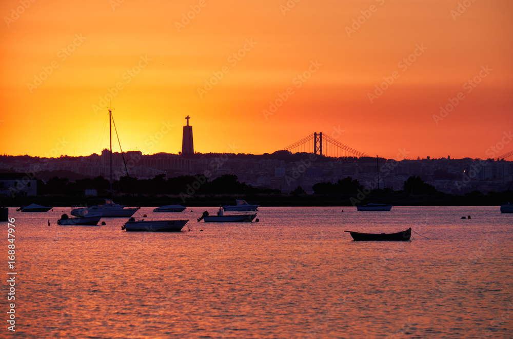 Sunset over the river Tejo, 25th of April Bridge and statue of  Christ the King in Lisbon, Portugal