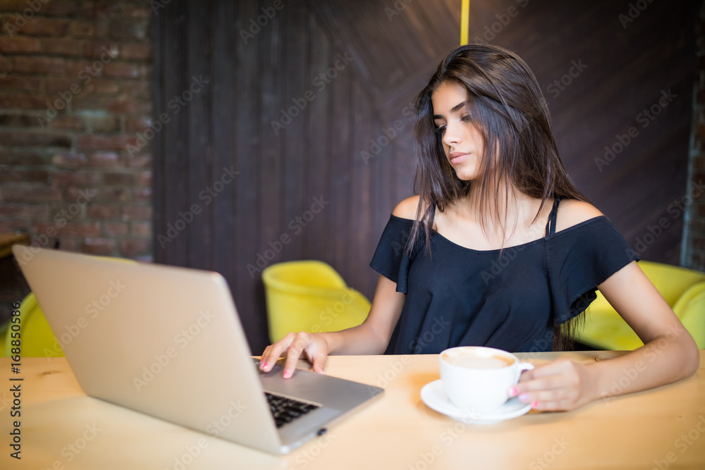 Fototapeta premium Beautiful brunette using laptop in cafe