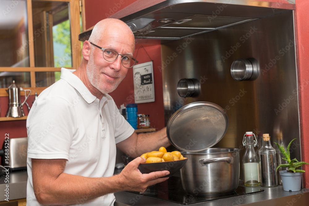 Mature handsome man cooking in home kitchen