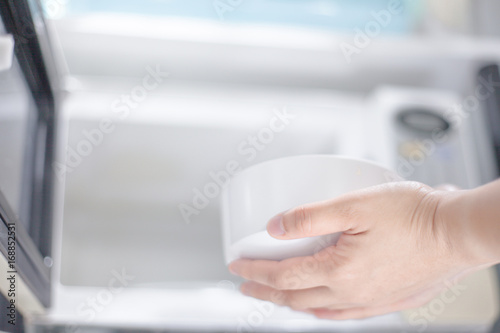 woman hand using are bringing food into the microwave oven at home. To reheat frozen food for their . Cooking made easy concept .