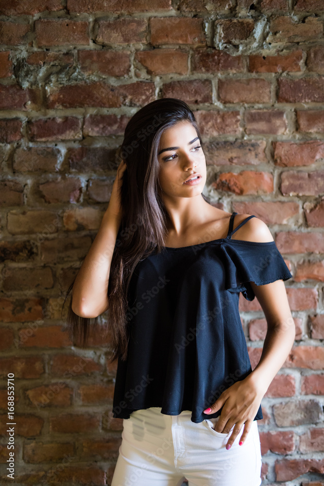 Young beautiful happy woman in casual clothes against brick wall