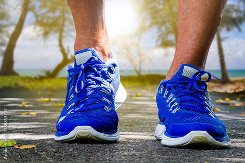 Man wearing sport shoes running on blurred beach background, sport exercise concept