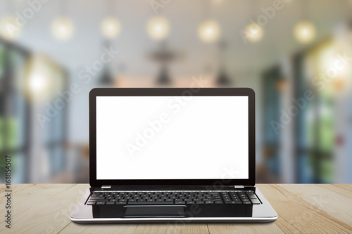 Laptop with blank white screen on vintage wooden table on blurred coffee shop background