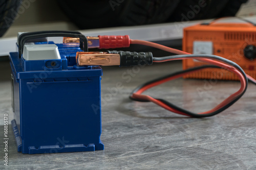 Recharging the car battery on a wooden background