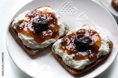 Breakfast with dark bread with white cheese and jam and coffee. 