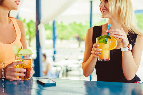 Cocktail in woman hand on the open terrace in bar during summer time
