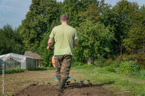 A man digs a garden with a cultivator