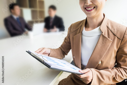 Portrait of a handsome young business women with people in background at office meeting.