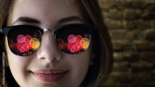 Cinemagraph - Firework reflected in young beautiful girl's sunglasses. Concept of celebrate. Motion Photo.