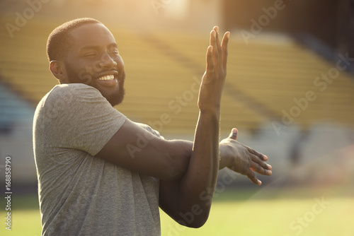 A handsome black man is performing stretching exersises for his arms in the field photo