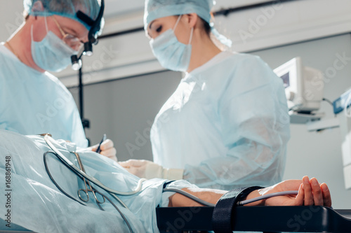 Horizontal shot of a female patient lying on operating table surgery room team of surgeons working photo