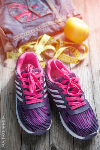 Sport shoes, apples and measuring tape on wooden background top view. Sport equipment.