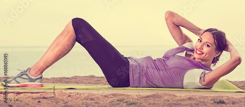 Woman doing exercises on beach by ocean