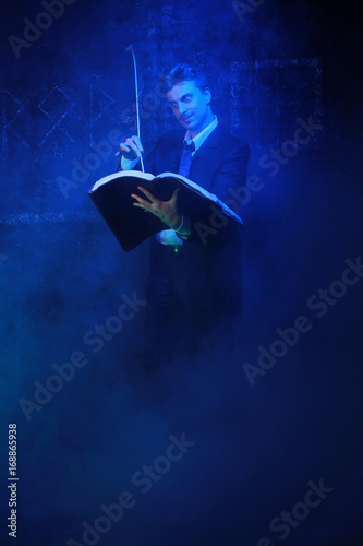 handsome mystic writer standing on black background in the smoke photo