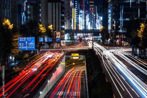 Busy crossroad in Tokyo at night long exposure red light traces tunnel dark illumination